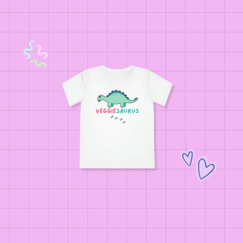 White toddler tee stegosaurus illustration that says 'Veggiesaurus' on a pink background 