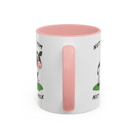 A white ceramic mug with a pink interior, pink handle, and a cartoon cow graphic with partial text on the side, shown on a plain white background.