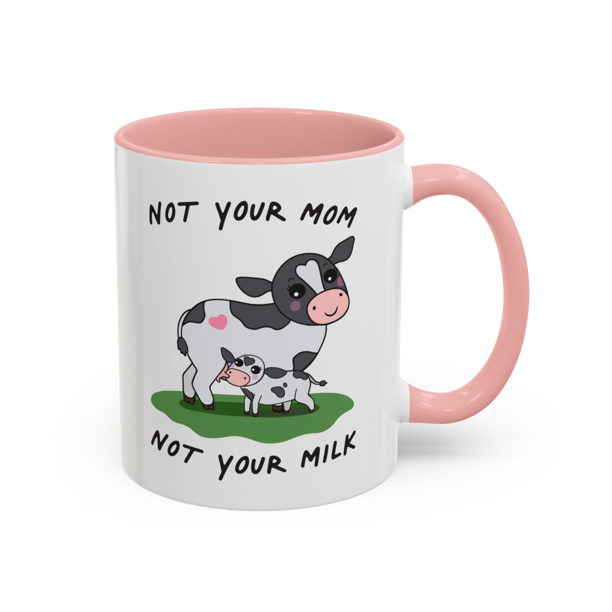 A white ceramic coffee mug with a pink interior, handle, and rim. The front features an illustration of a black-and-white cow and a calf on a green patch of grass, with the text 'NOT YOUR MOM' above and 'NOT YOUR MILK' below.