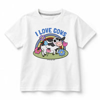 A white short-sleeve kids' t-shirt featuring a colorful cartoon graphic of a cow in front of a rainbow with the text 'I LOVE COWS' in blue. The brand 'LITTLE ONE SHOP' is printed below the graphic.