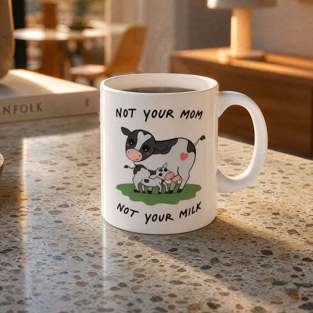 Mug with Bo the cow illustration and text "Not your cow, not your milk" on a countertop 