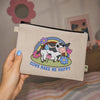 Beige pouch with cow illustration and 'Cows Make Me Happy' text held by a hand.