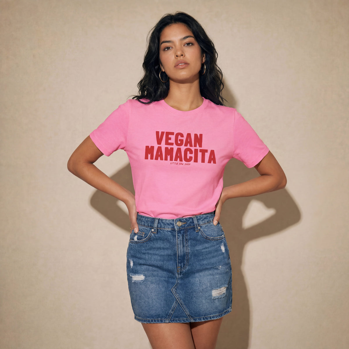 Woman wearing a pink t-shirt with 'VEGAN MANACITA' red text on a beige background