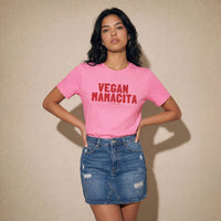 Woman wearing a pink t-shirt with 'VEGAN MANACITA' red text on a beige background