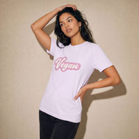 Woman wearing a white t-shirt with 'Vegan' in pink text against a beige background