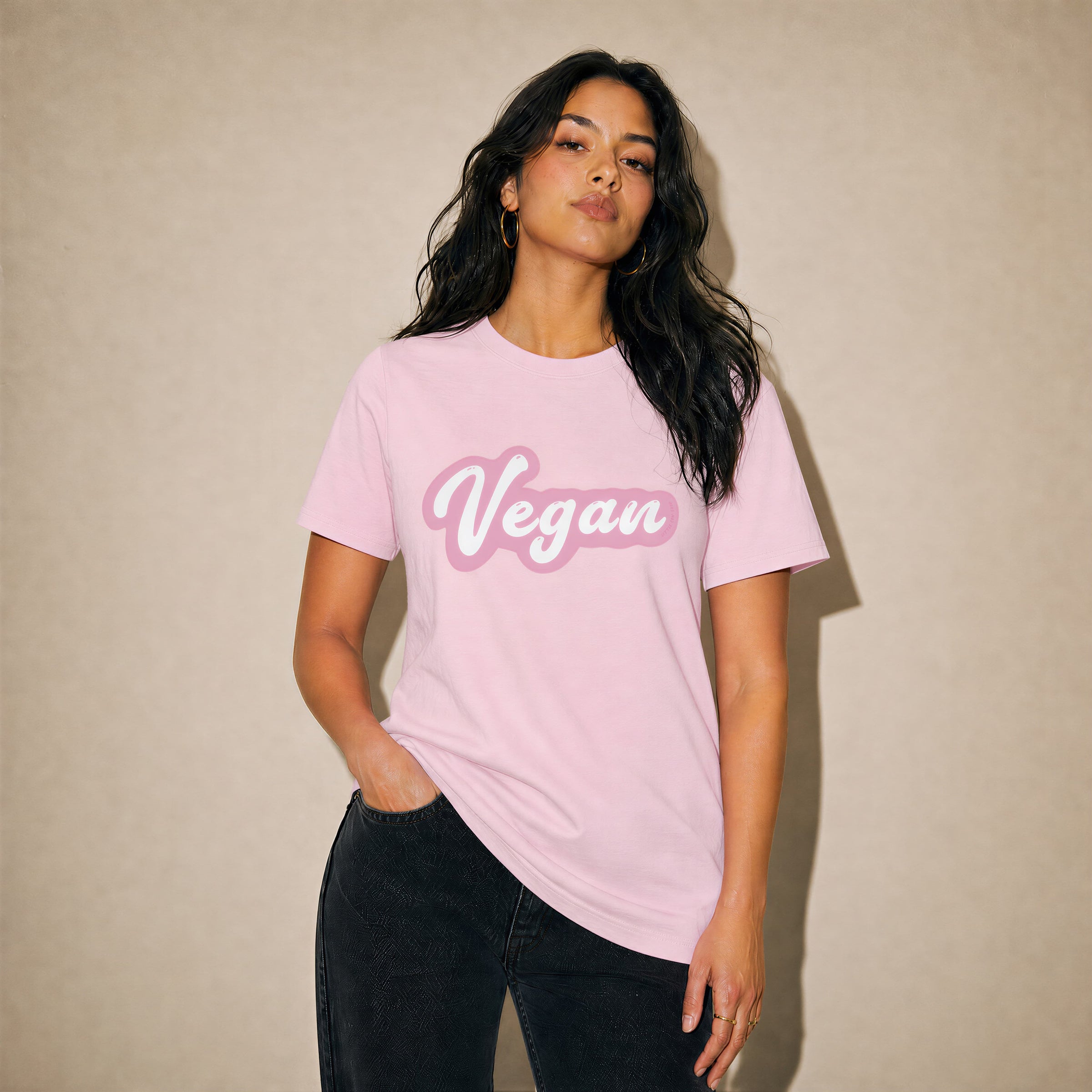 Woman wearing a pink t-shirt with 'Vegan' text against a beige background